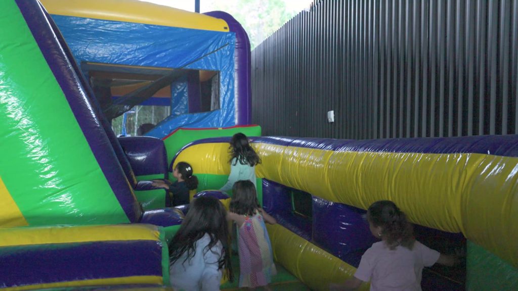 Children climbing through a colorful bounce house in the kids' zone at La Fiesta Hispana