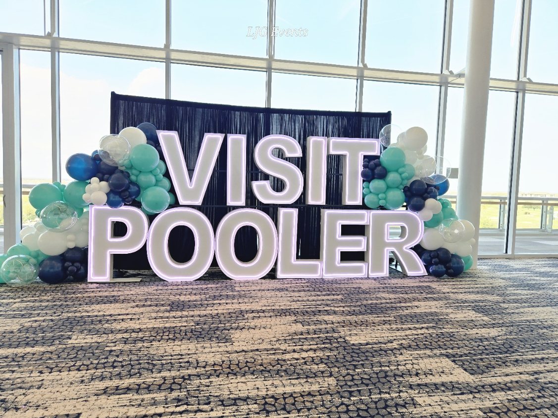 Illuminated three-foot Visit Pooler marquee letters surrounded by a teal, navy and white balloon garland by Stellar Marquees Savannah